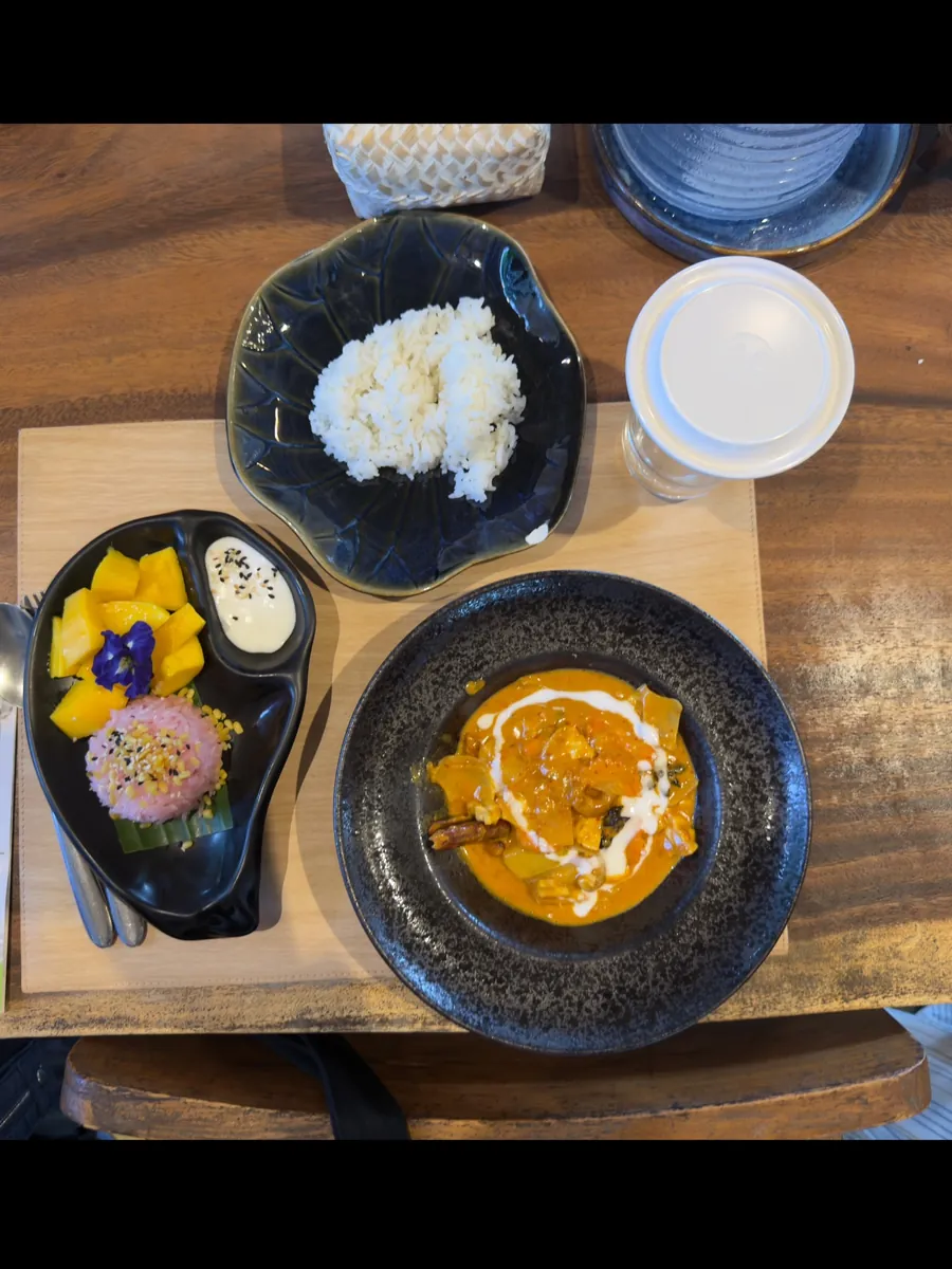 Curry, rice and mango sticky rice on a wooden table