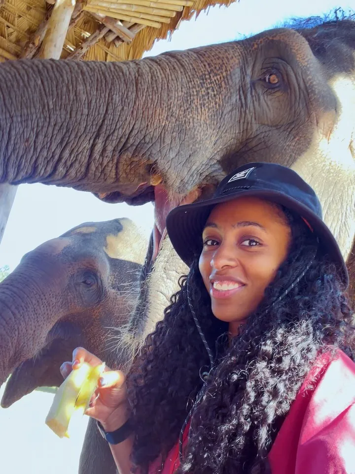 Kay smiling while feeding an elephant