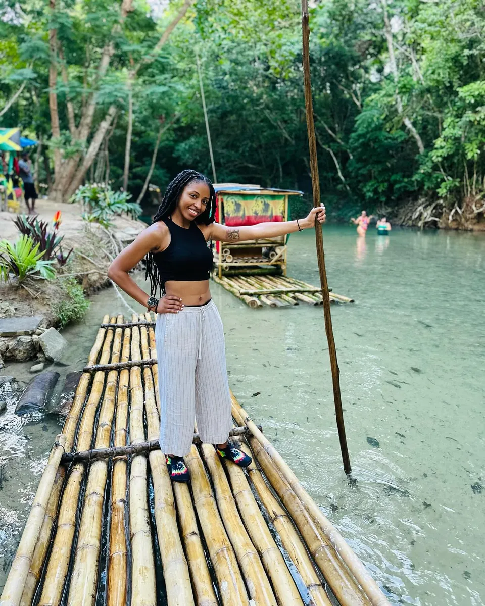Kay standing on a bamboo raft on a clear river