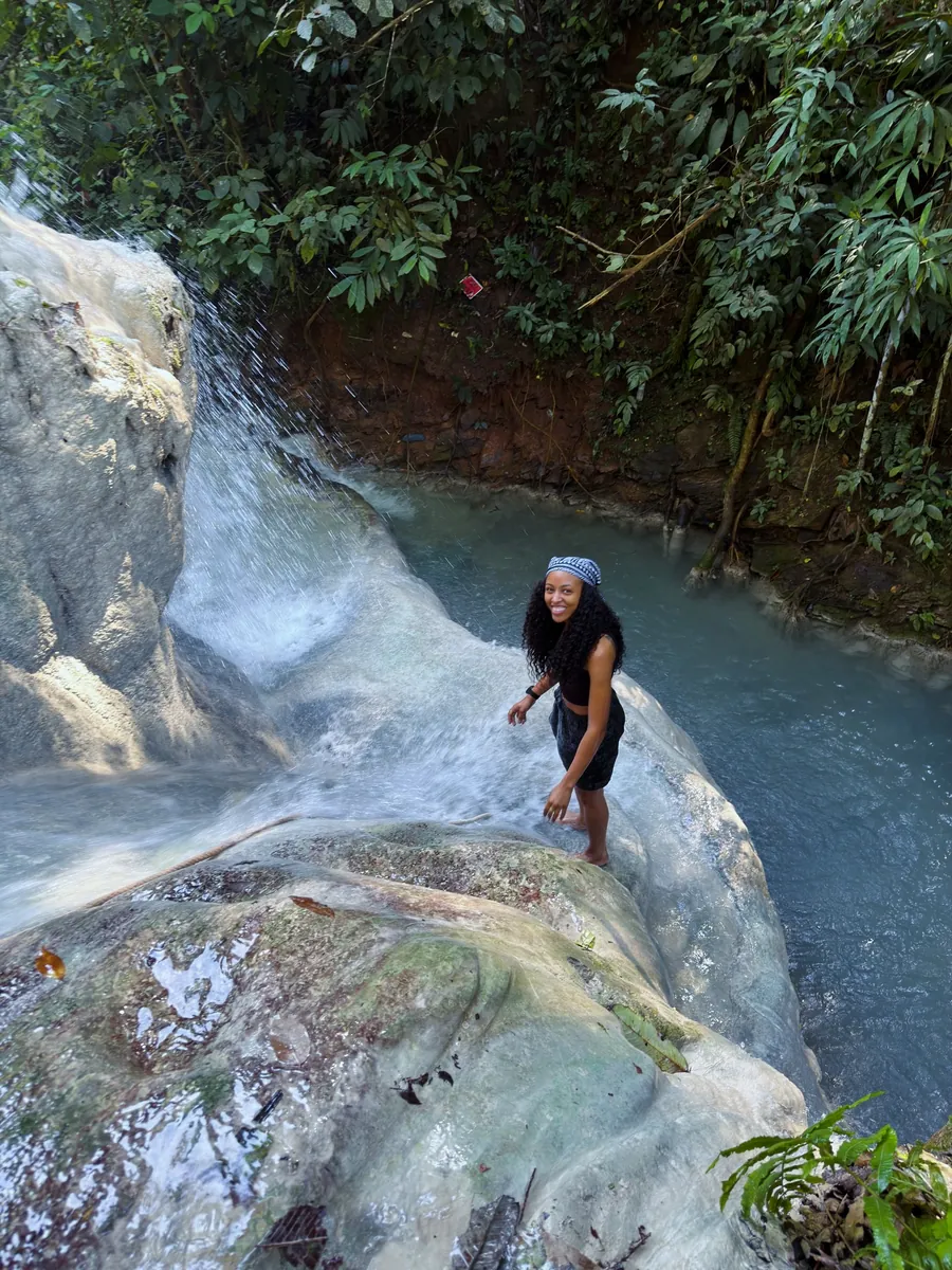 Kay climbing a white limestone waterfall in the jungle